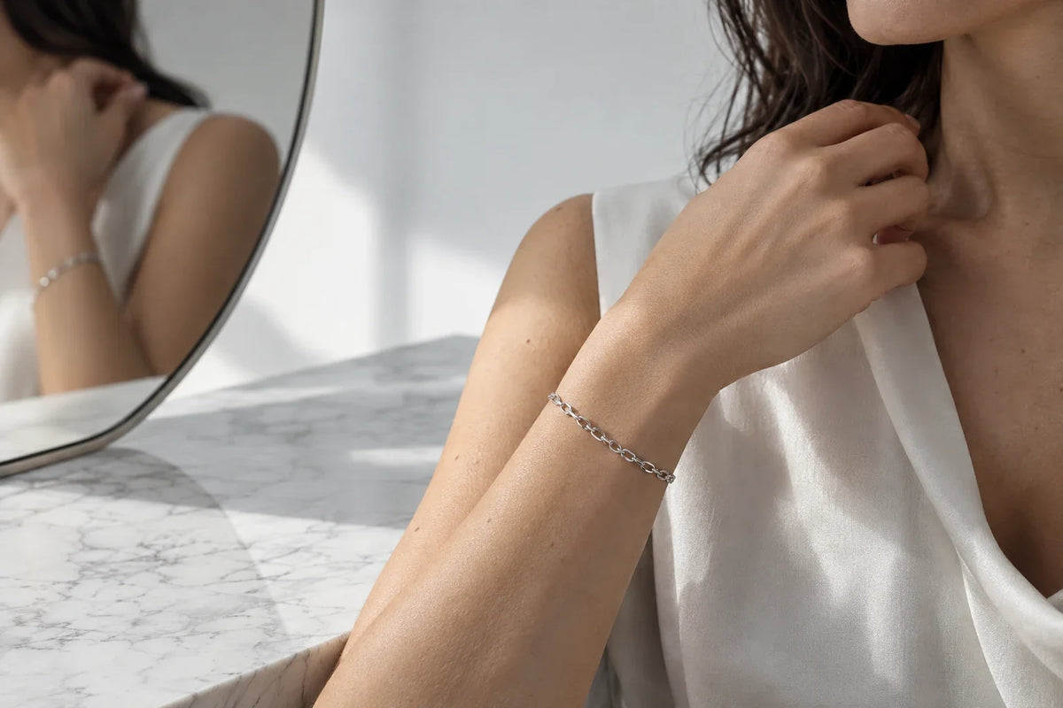 Bracciale in acciaio 316L lucido su superficie di marmo bianco, luce naturale laterale