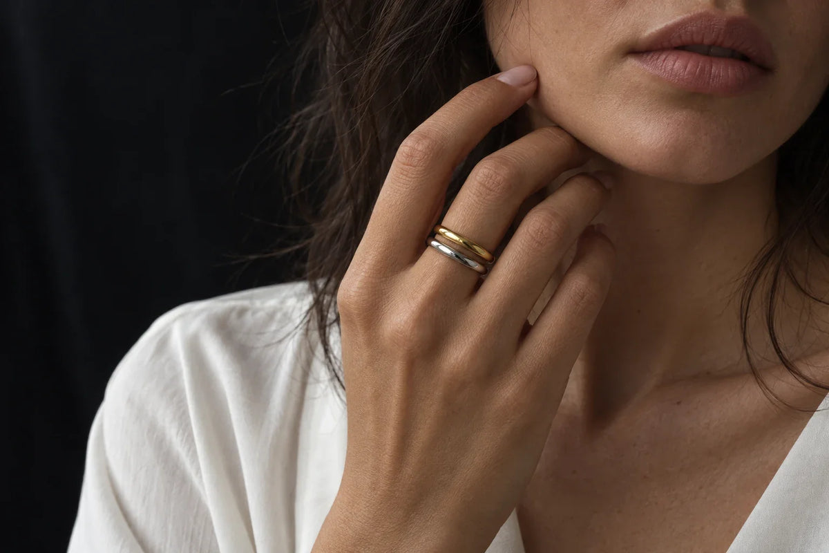 Anelli a fascetta sottile in acciaio 316L e argento 925 sovrapposti su mano femminile