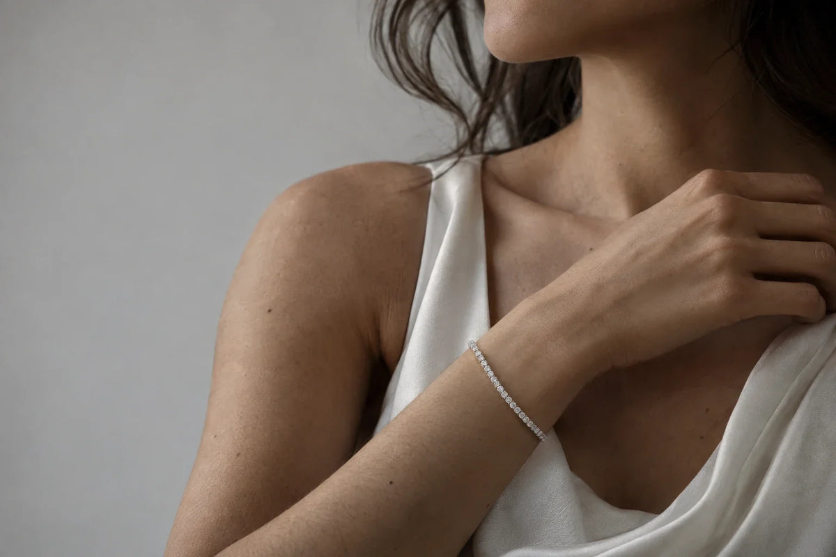Bracciale tennis in argento 925 indossato su polso femminile, sfondo neutro chiaro