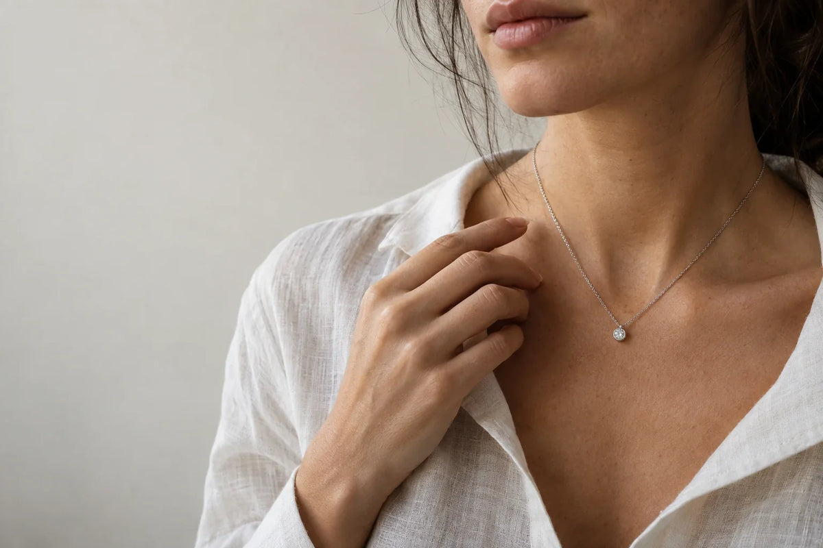 Selezione di gioielli in argento 925 e acciaio 316L disposti su superficie in lino naturale, luce naturale laterale